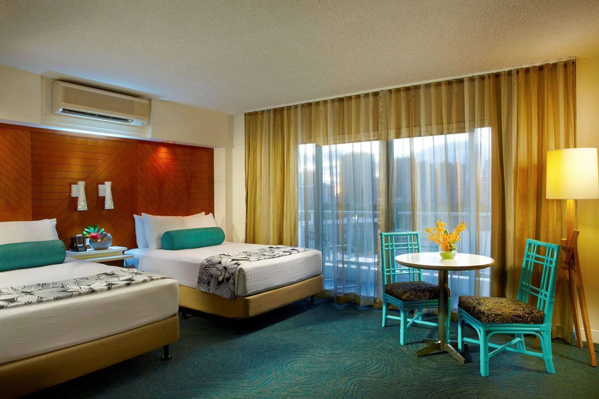Superior Room with two beds, table seating, and balcony curtains at Oasis Hotel Waikiki.