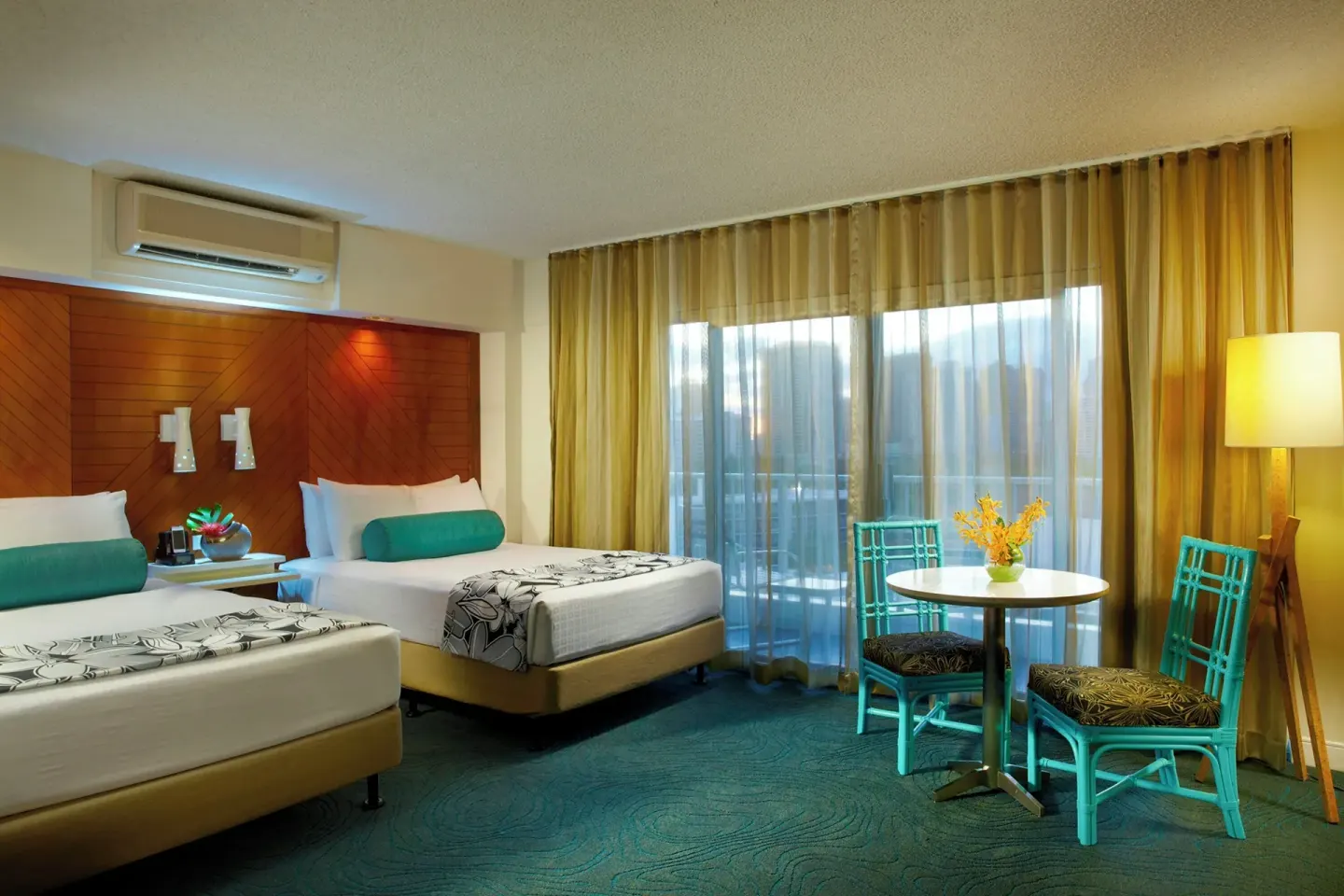 Superior Room with two beds, bedside lighting, and a small dining table at Oasis Hotel Waikiki.