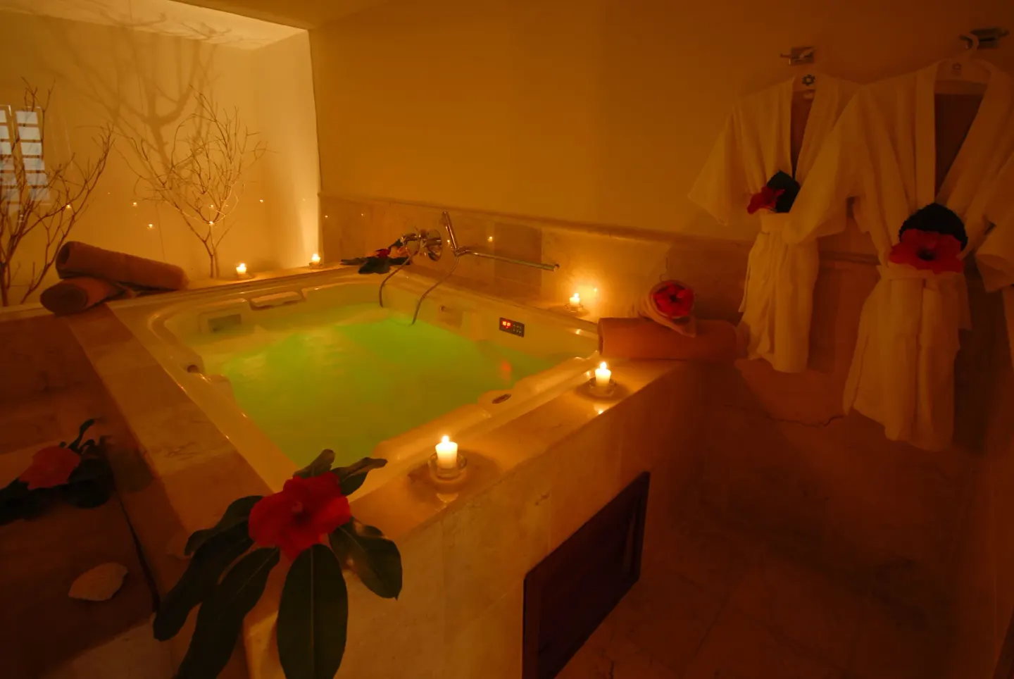 Candlelit spa tub with robes and floral accents at Oasis Palm.