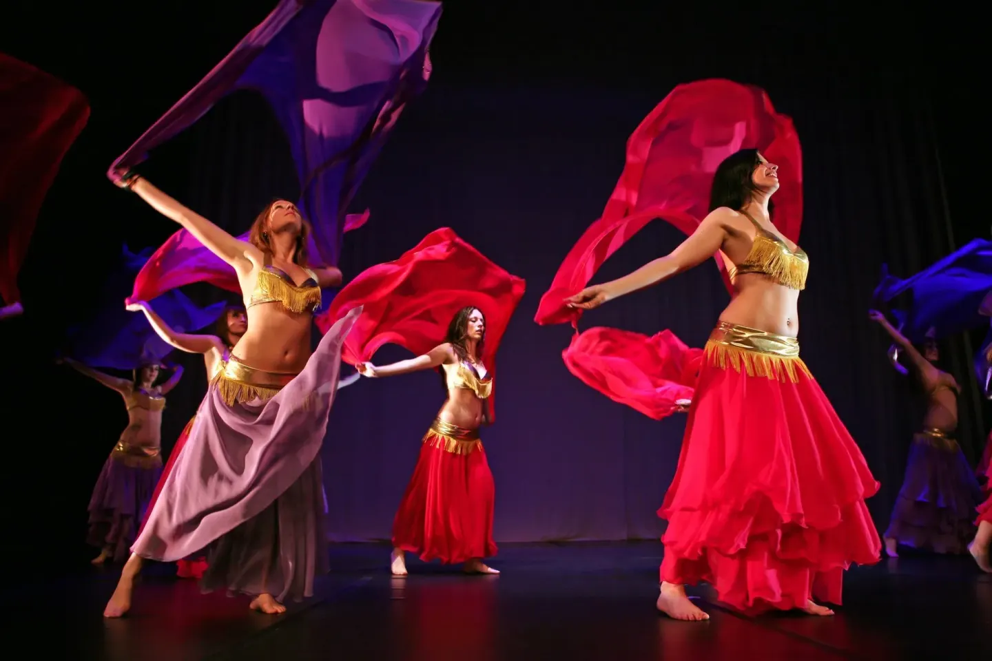 Costumed dancers wave colorful fabric on a stage at Oasis Palm.