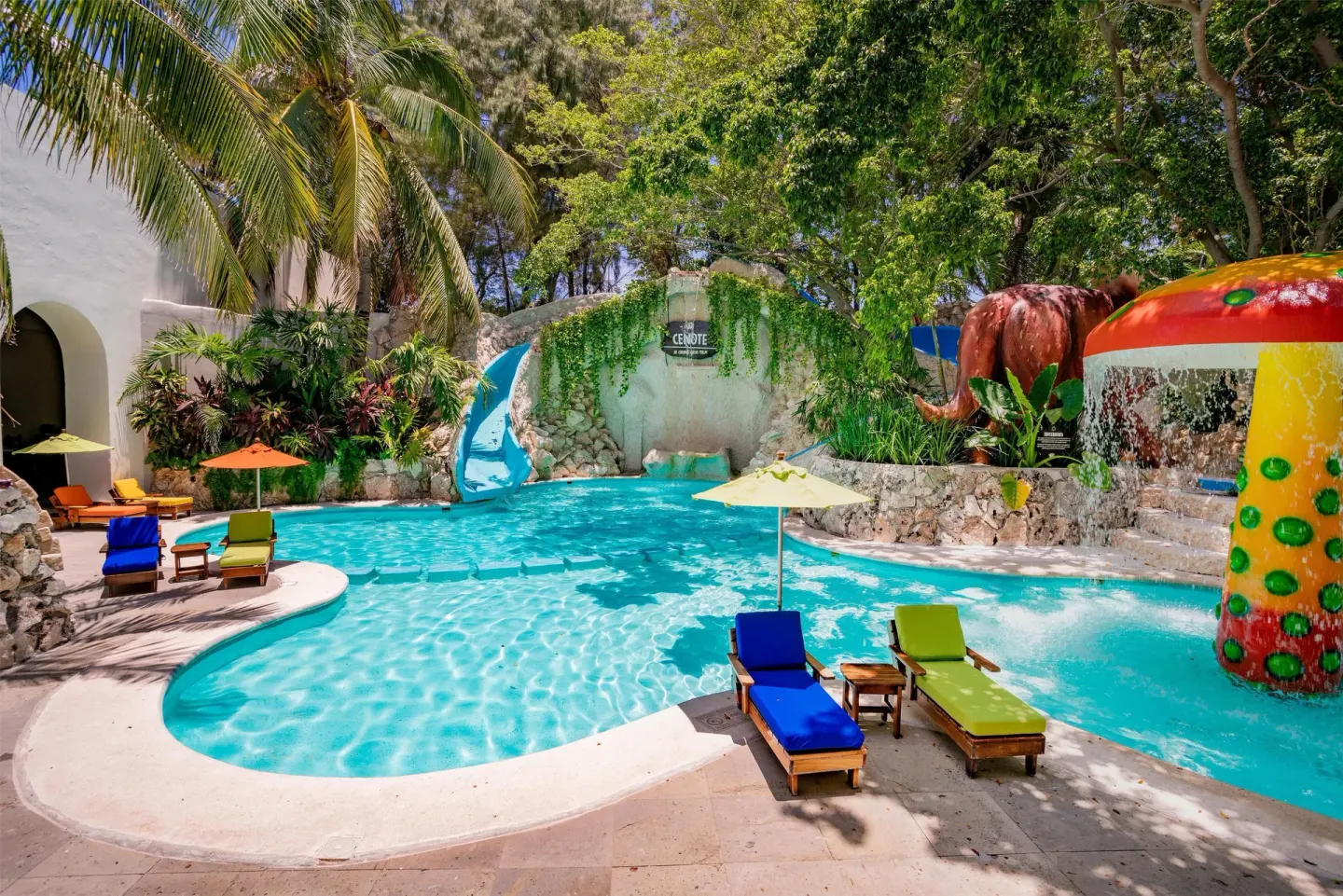 Curved pool with colorful loungers, slides, and water spray features at Oasis Palm.