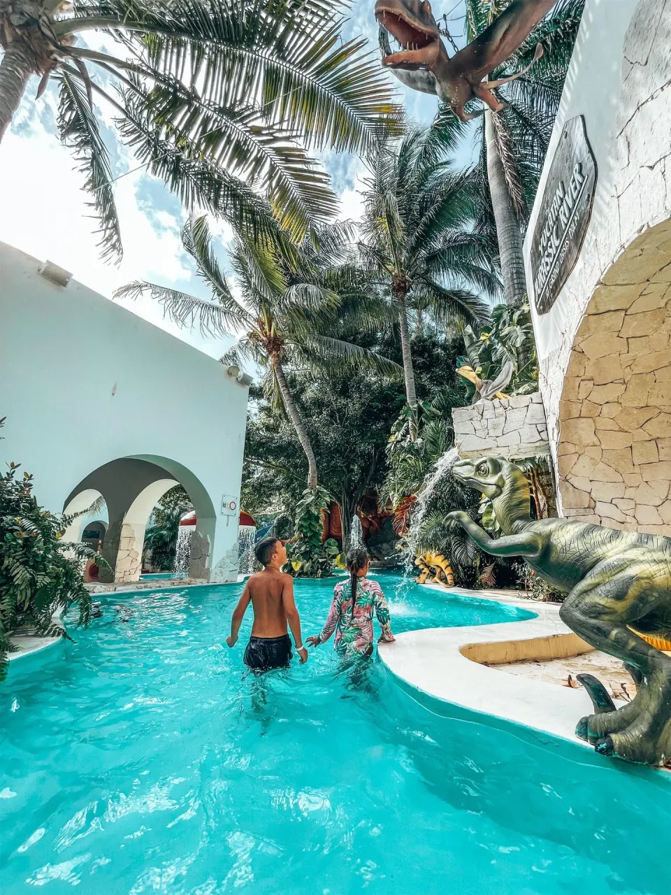 Children wade through a dinosaur-themed pool area at Oasis Palm.