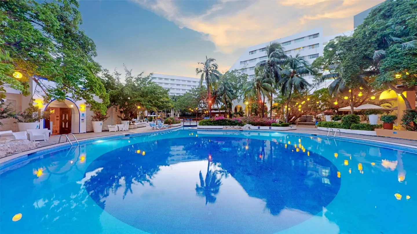 Large resort pool reflecting palms and lights at Oasis Palm.