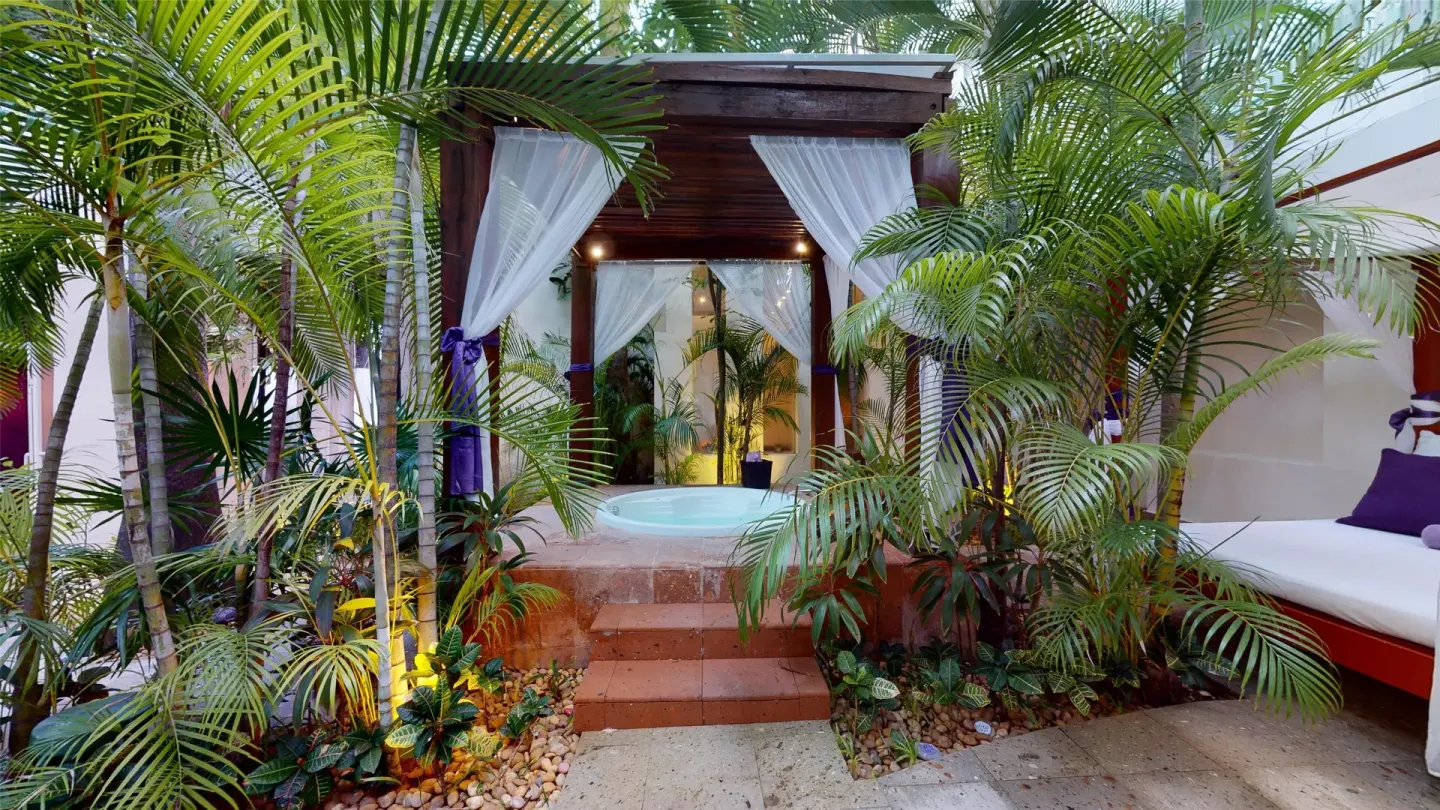 A private whirlpool terrace framed by palms and white curtains at Oasis Palm.