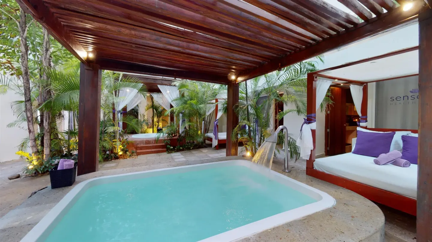 Outdoor spa soaking tub with cabana beds and palms at Oasis Palm.