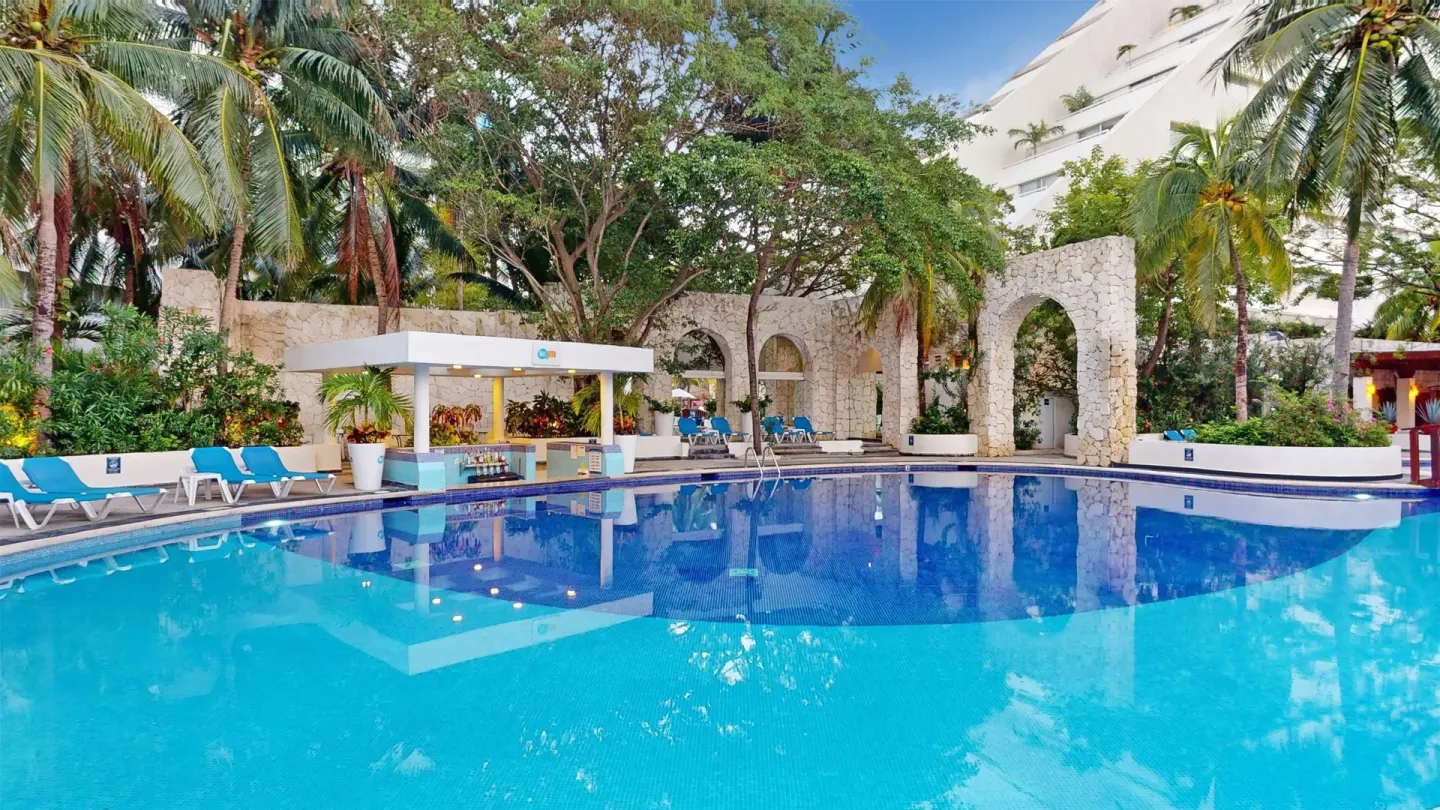 Pool with blue loungers, palms, and stone arches at Oasis Palm.
