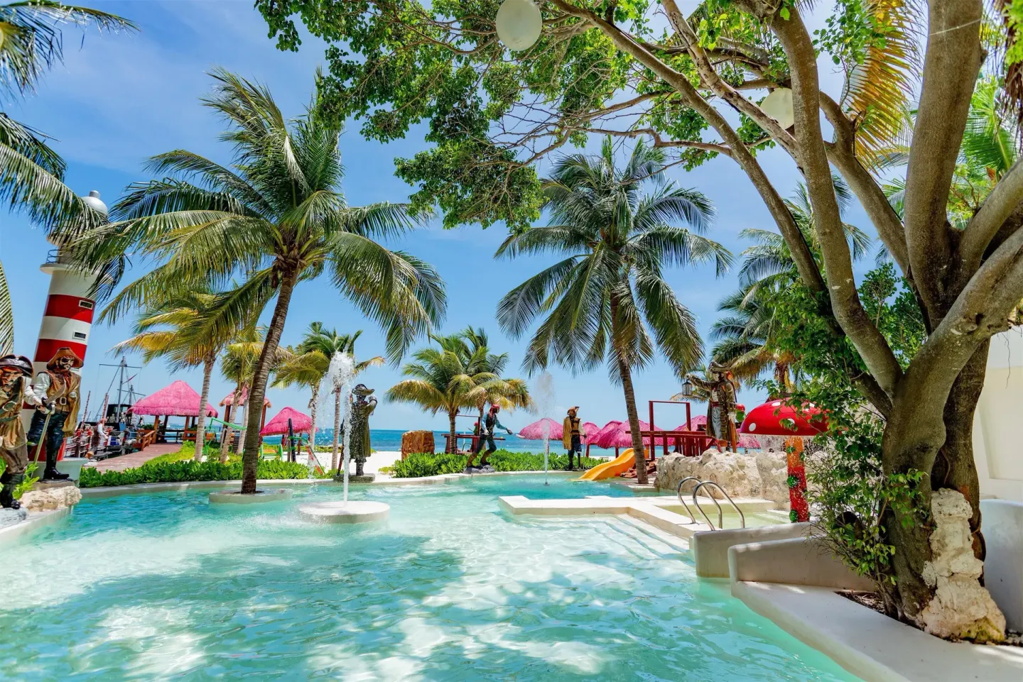 Shallow pool with palm trees, fountain, and ocean beyond at Oasis Palm.