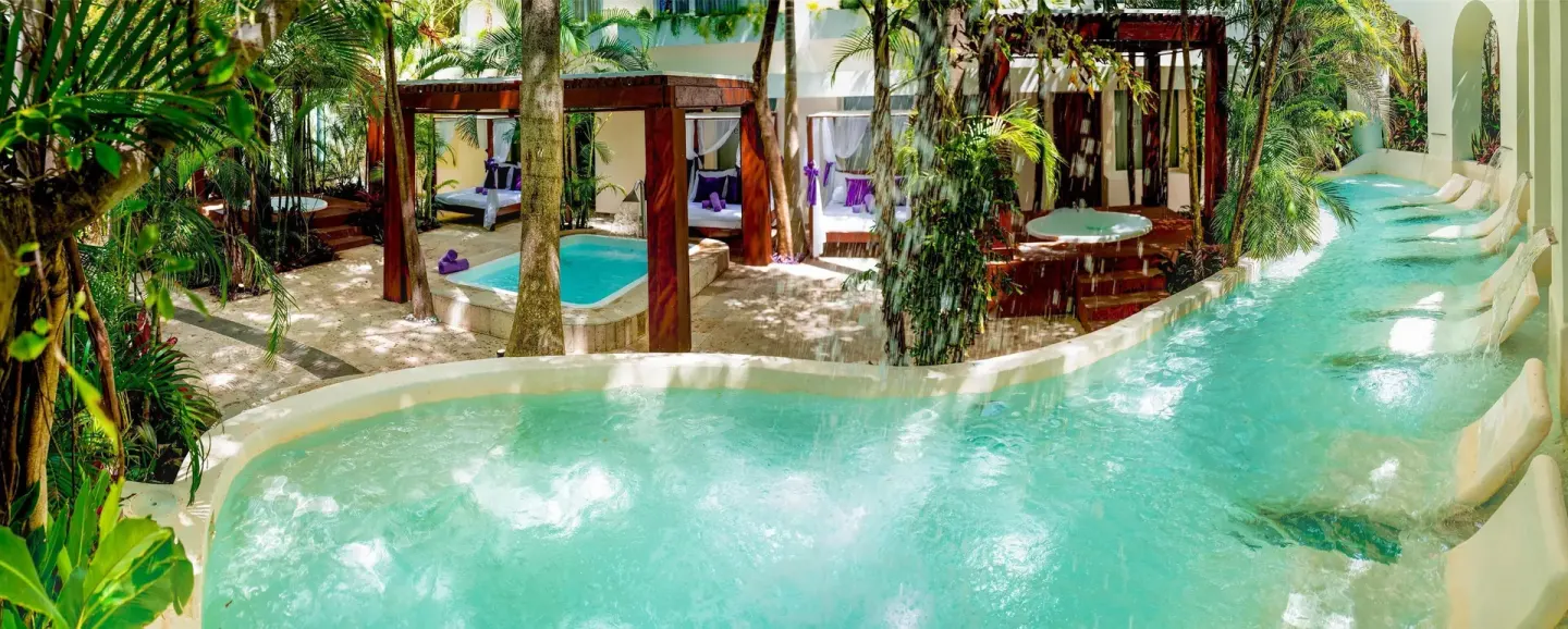 A leafy pool courtyard with cabanas and turquoise water at Oasis Palm.