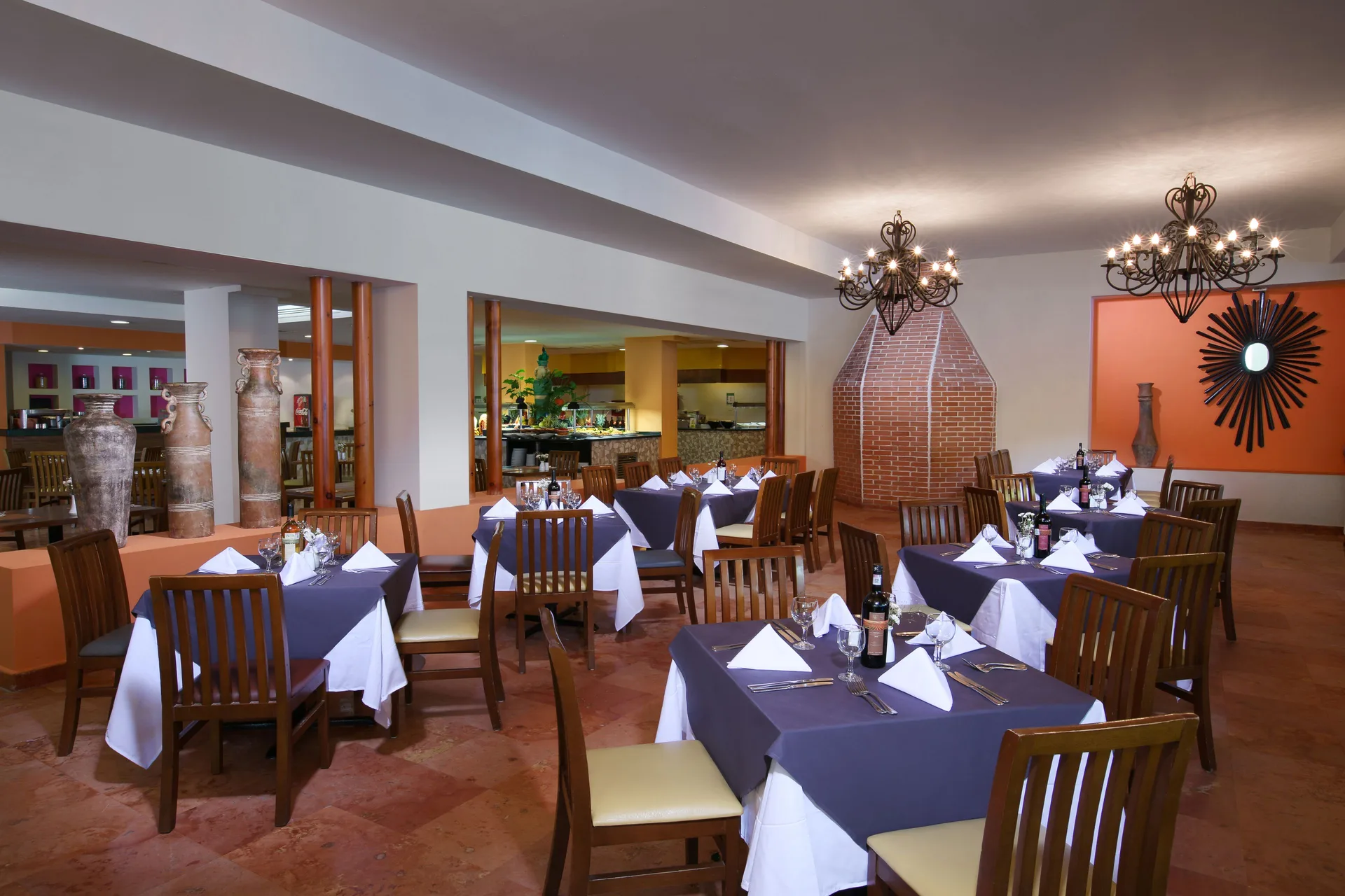 Dining room with set tables, chandeliers, and warm decor at Oasis Palm.