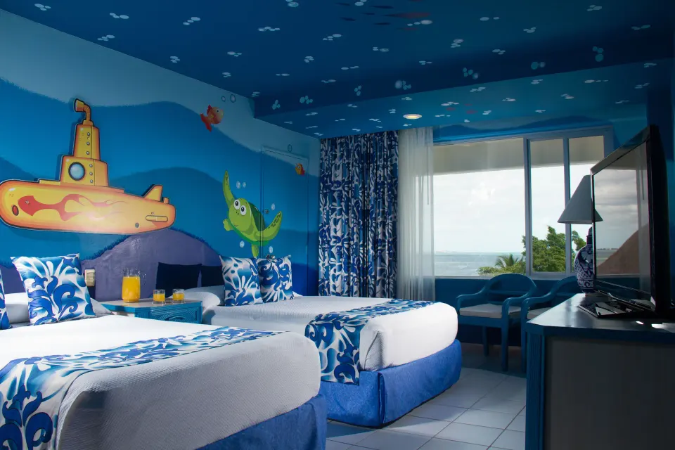 Family room at Oasis Palm with two double beds, blue sea-life murals, a TV, and a window with water beyond.