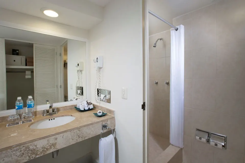 Standard room bathroom with sink, mirror, and shower curtain at Oasis Palm.