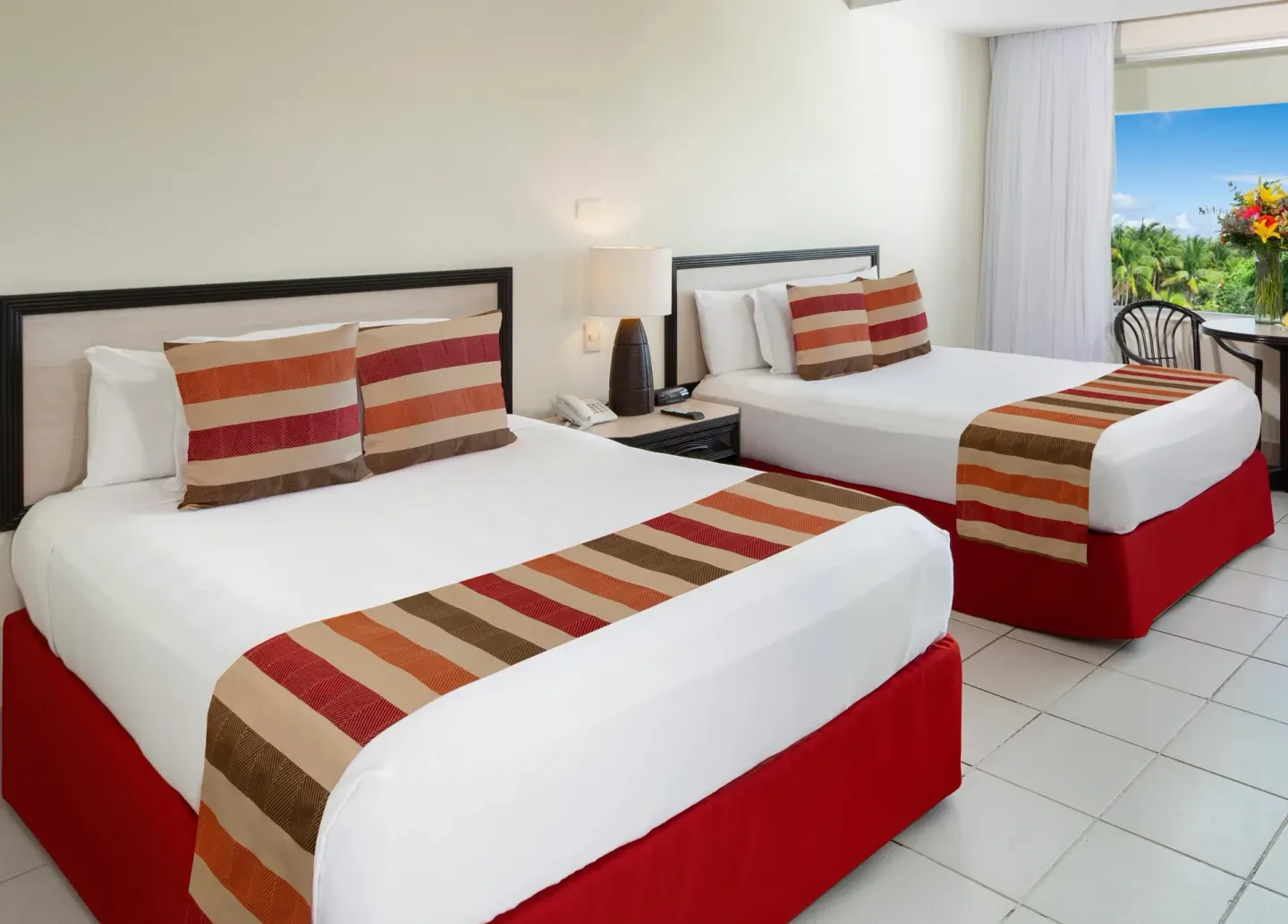 Standard guest room with two beds, striped runners, and bedside table at Oasis Palm.