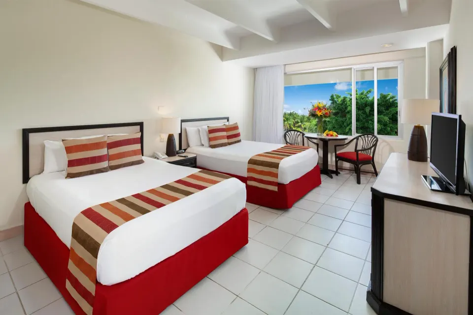 Standard guest room with two beds, TV cabinet, and table by the window at Oasis Palm.