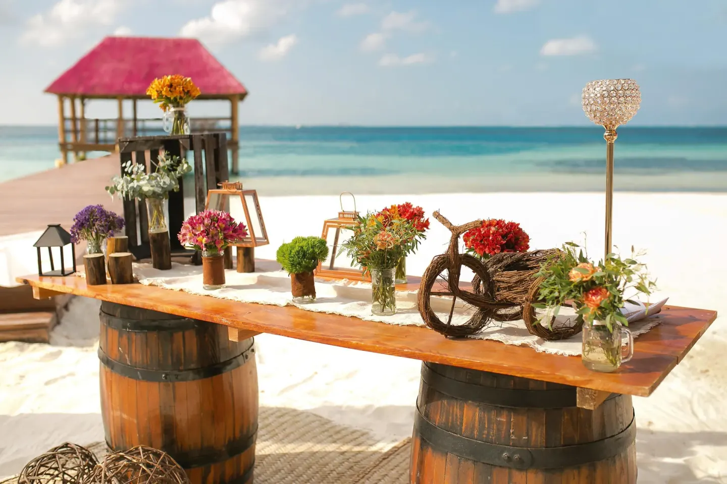 Beach wedding décor with flowers, lanterns and barrels by the ocean at Oasis Palm.