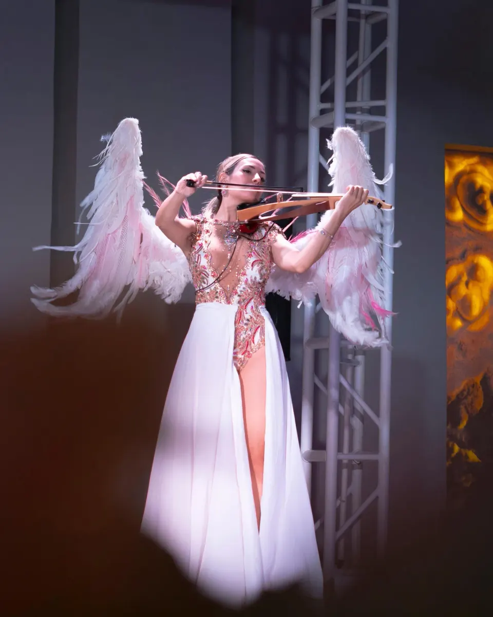 A violinist in winged costume performs onstage at Oasis Palm.