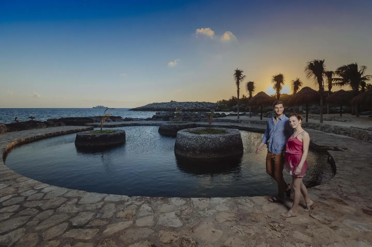 Couple walks by the oceanfront lagoon at Occidental at Xcaret Destination.