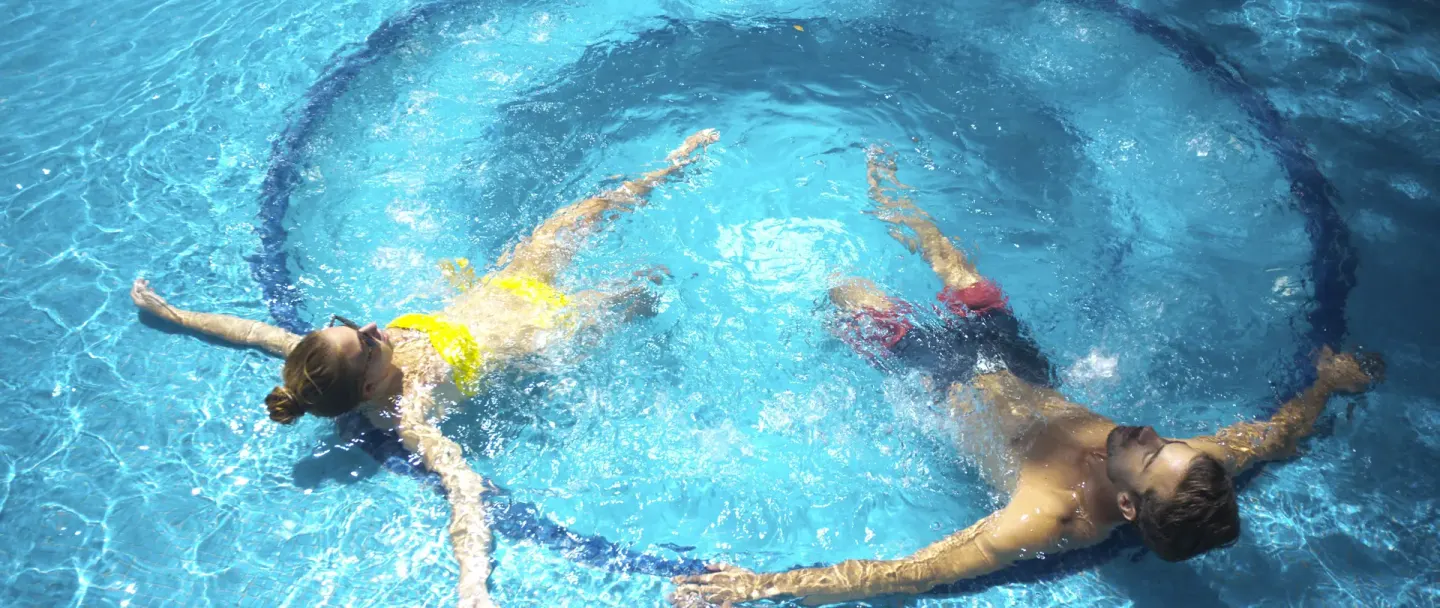 Two guests float on their backs in a blue pool at Occidental at Xcaret Destination.