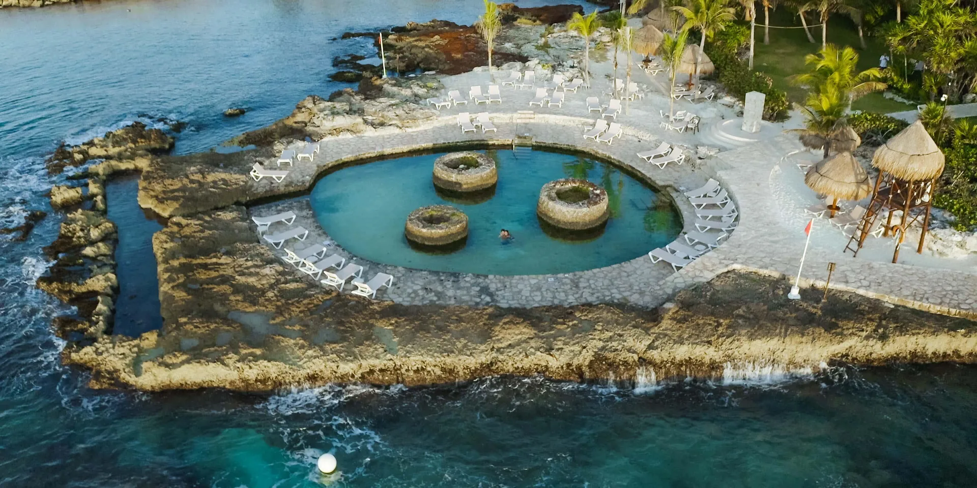 Oceanfront circular pool with loungers and palapa shade at Occidental at Xcaret Destination.