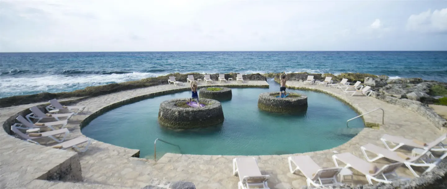 Stone oceanfront pool with loungers at Occidental at Xcaret Destination.