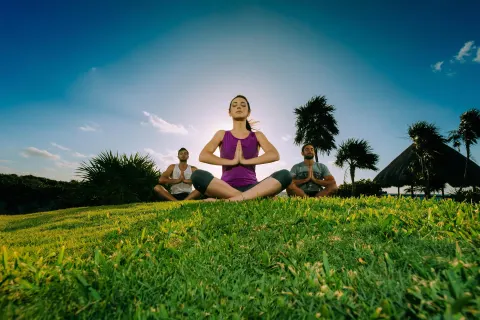 Outdoor yoga session on the grass at Occidental at Xcaret Destination.
