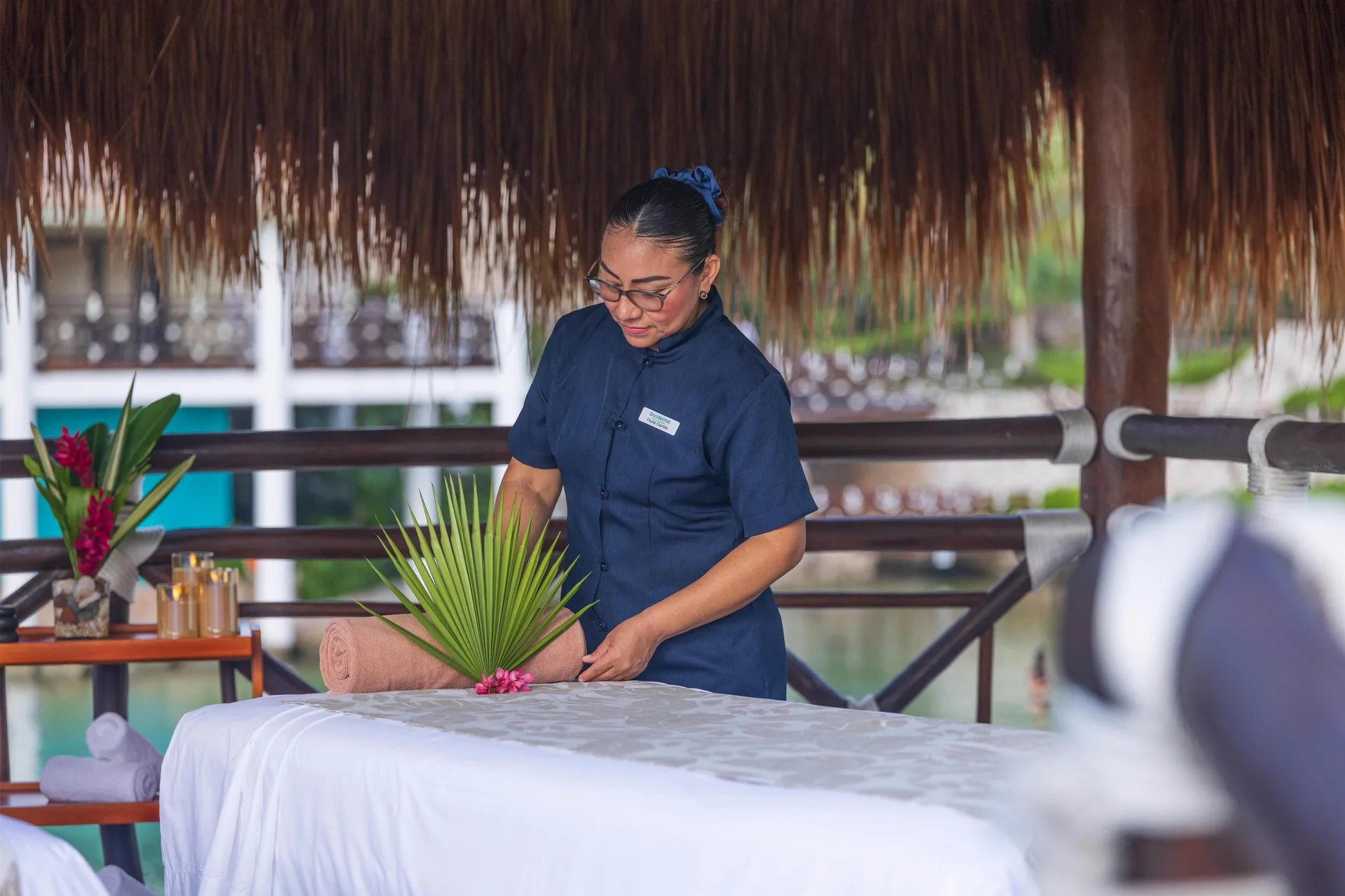 Spa attendant prepares a massage table under a palapa at Occidental at Xcaret Destination.