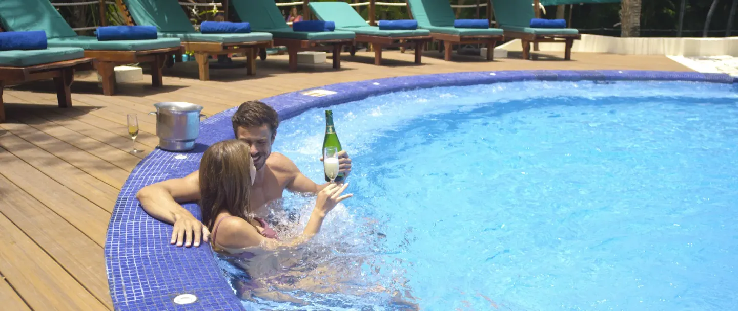 A couple toasts with sparkling wine in the pool at Occidental at Xcaret Destination.