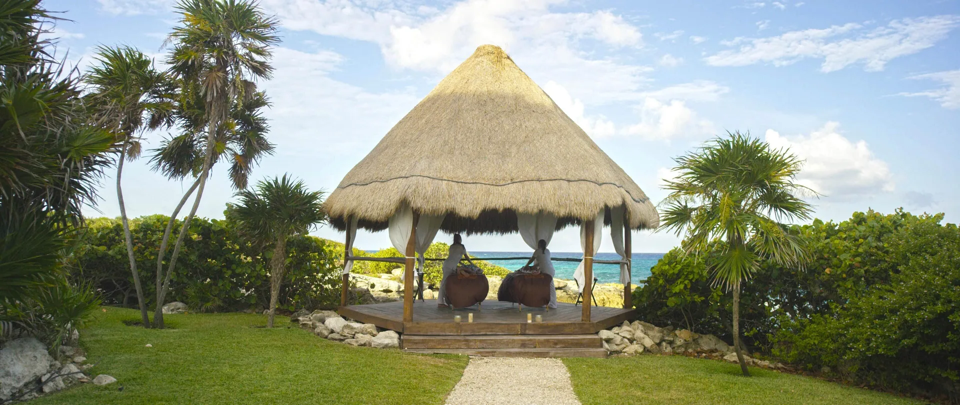 Thatched seaside palapa with two loungers at Occidental at Xcaret Destination.