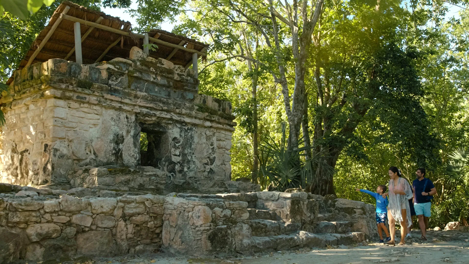 Guests walk beside a stone ruin in the trees at Occidental at Xcaret Destination.