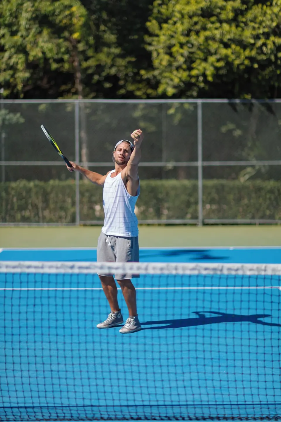 A tennis player serves on a blue court at Occidental at Xcaret Destination.