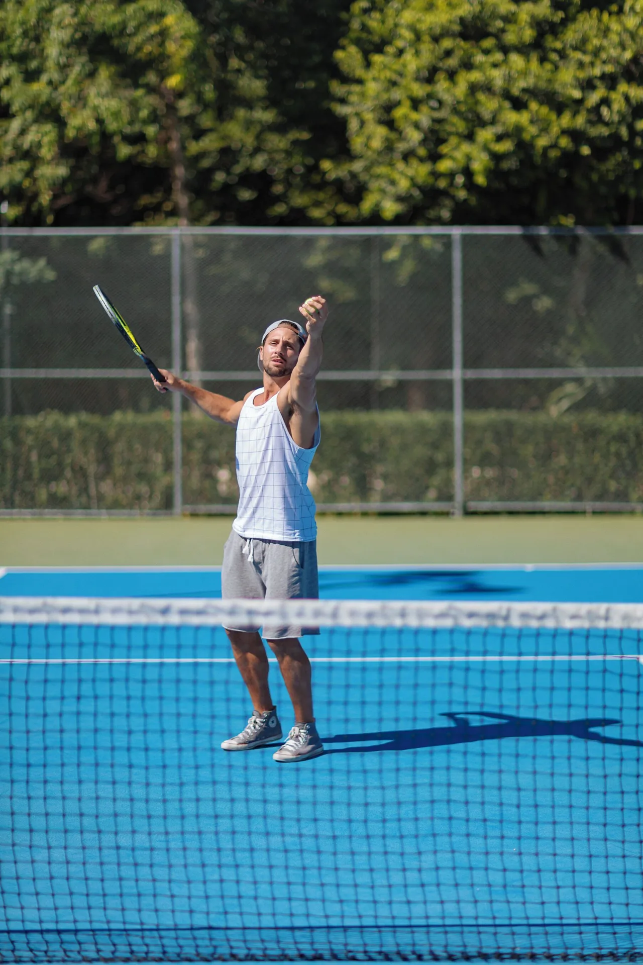 A tennis player serves on a blue court at Occidental at Xcaret Destination.