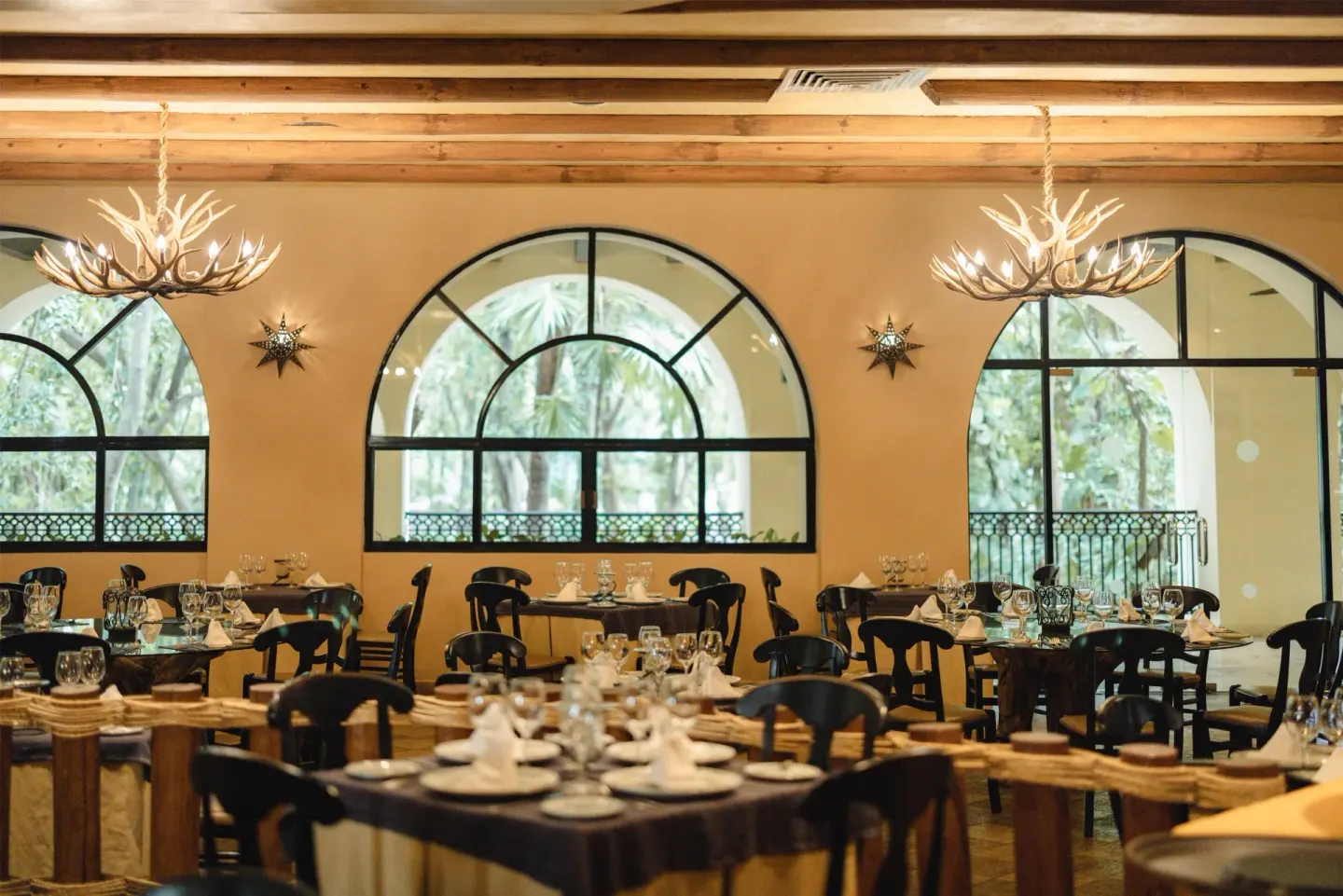 Dining room with arched windows and chandeliers at Occidental at Xcaret Destination.