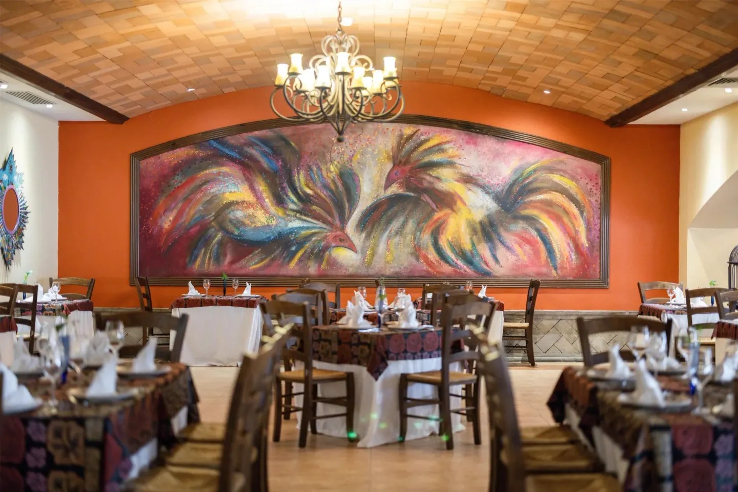 Restaurant dining room with rooster mural at Occidental at Xcaret Destination.
