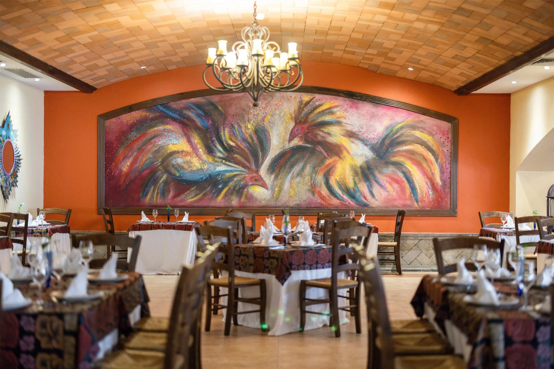 Restaurant dining room with rooster mural at Occidental at Xcaret Destination.