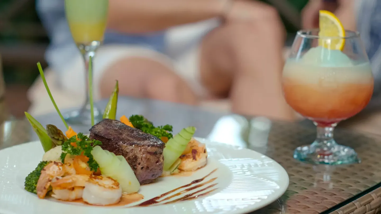 Plated steak and shrimp with cocktails at Occidental at Xcaret Destination.