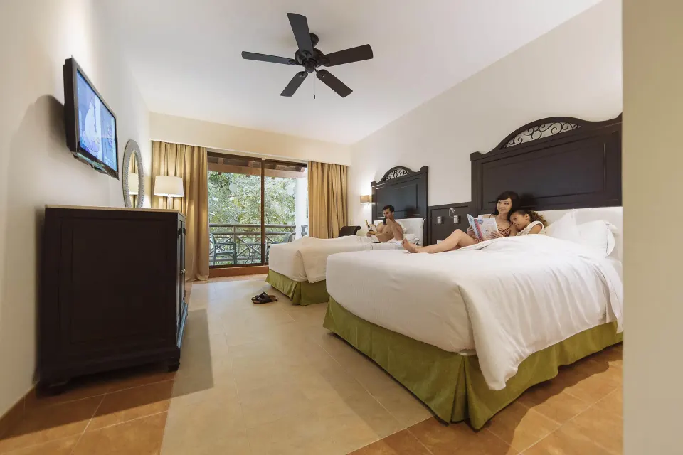 Deluxe Room with two beds, balcony and guests at Occidental at Xcaret Destination.