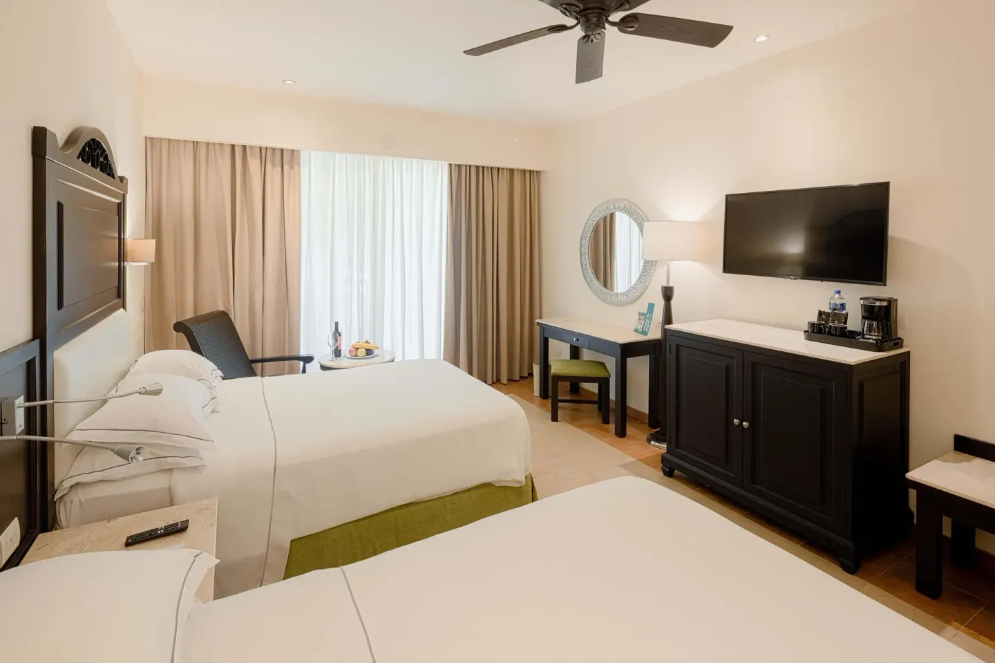 Deluxe Room with two beds, TV, desk and minibar cabinet at Occidental at Xcaret Destination.