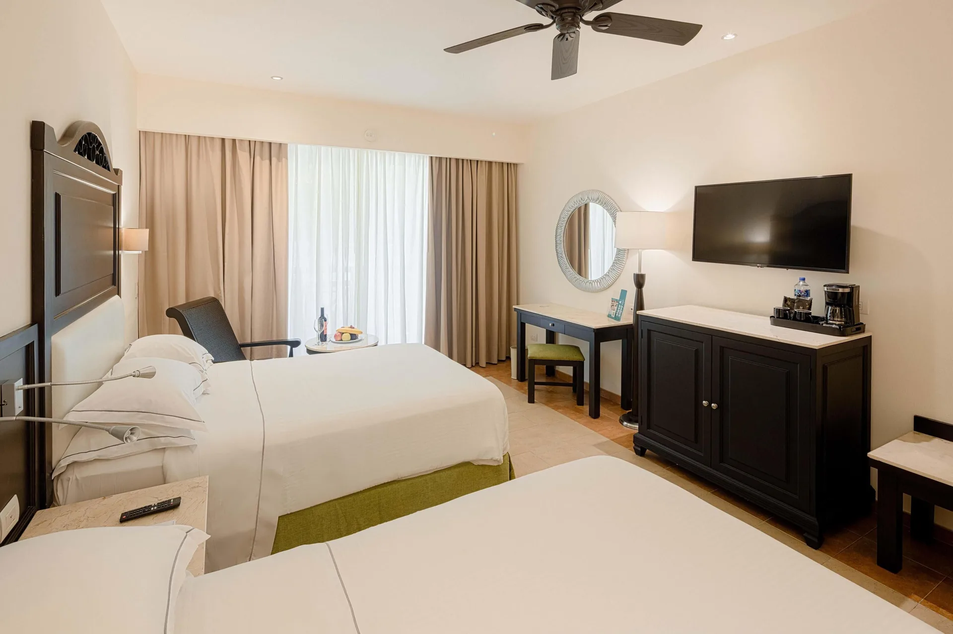 Deluxe Room with two beds, TV, desk and minibar cabinet at Occidental at Xcaret Destination.
