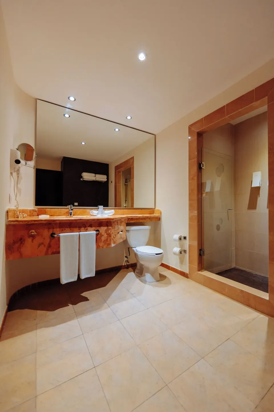 Junior Studio Suite bathroom with long vanity and glass shower at Occidental at Xcaret Destination.