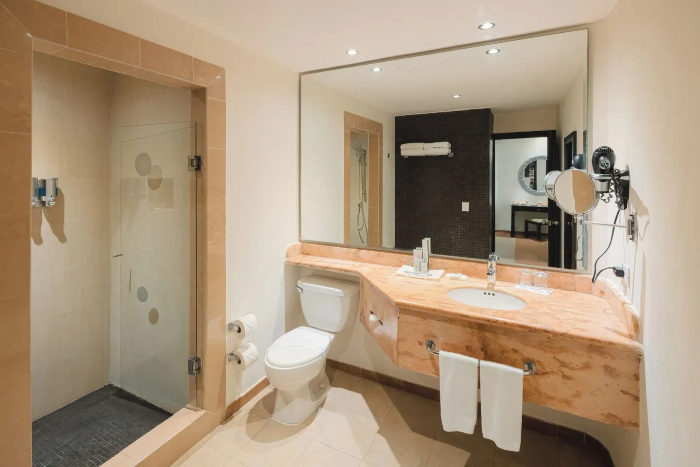 Junior Studio Suite bathroom with vanity, toilet, and glass shower at Occidental at Xcaret Destination.