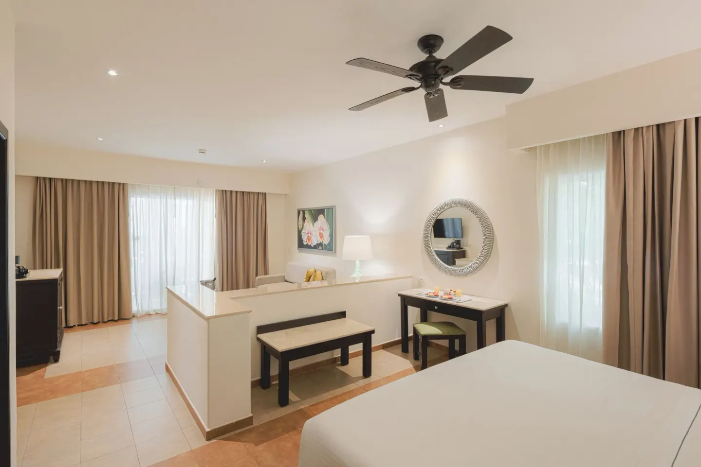 Junior Studio Suite with king bed, desk, bench, and curtained windows at Occidental at Xcaret Destination.