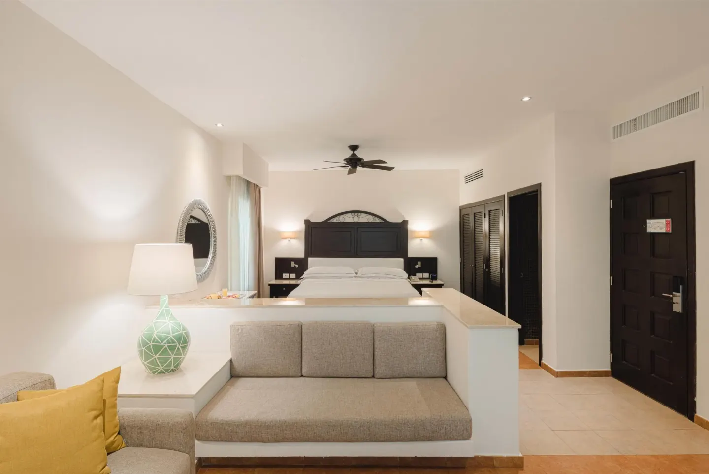 Junior Studio Suite with king bed, sofa, and entry door at Occidental at Xcaret Destination.