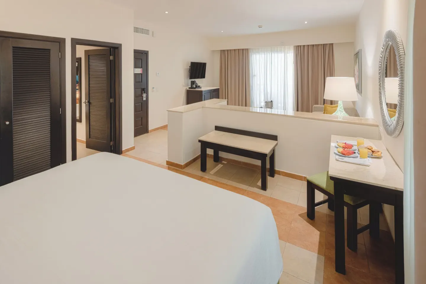 Junior Studio Suite with bed, TV, desk, and seating partition at Occidental at Xcaret Destination.
