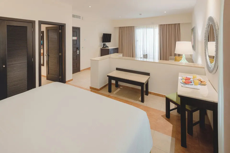 Junior Studio Suite with bed, TV, desk, and seating partition at Occidental at Xcaret Destination.