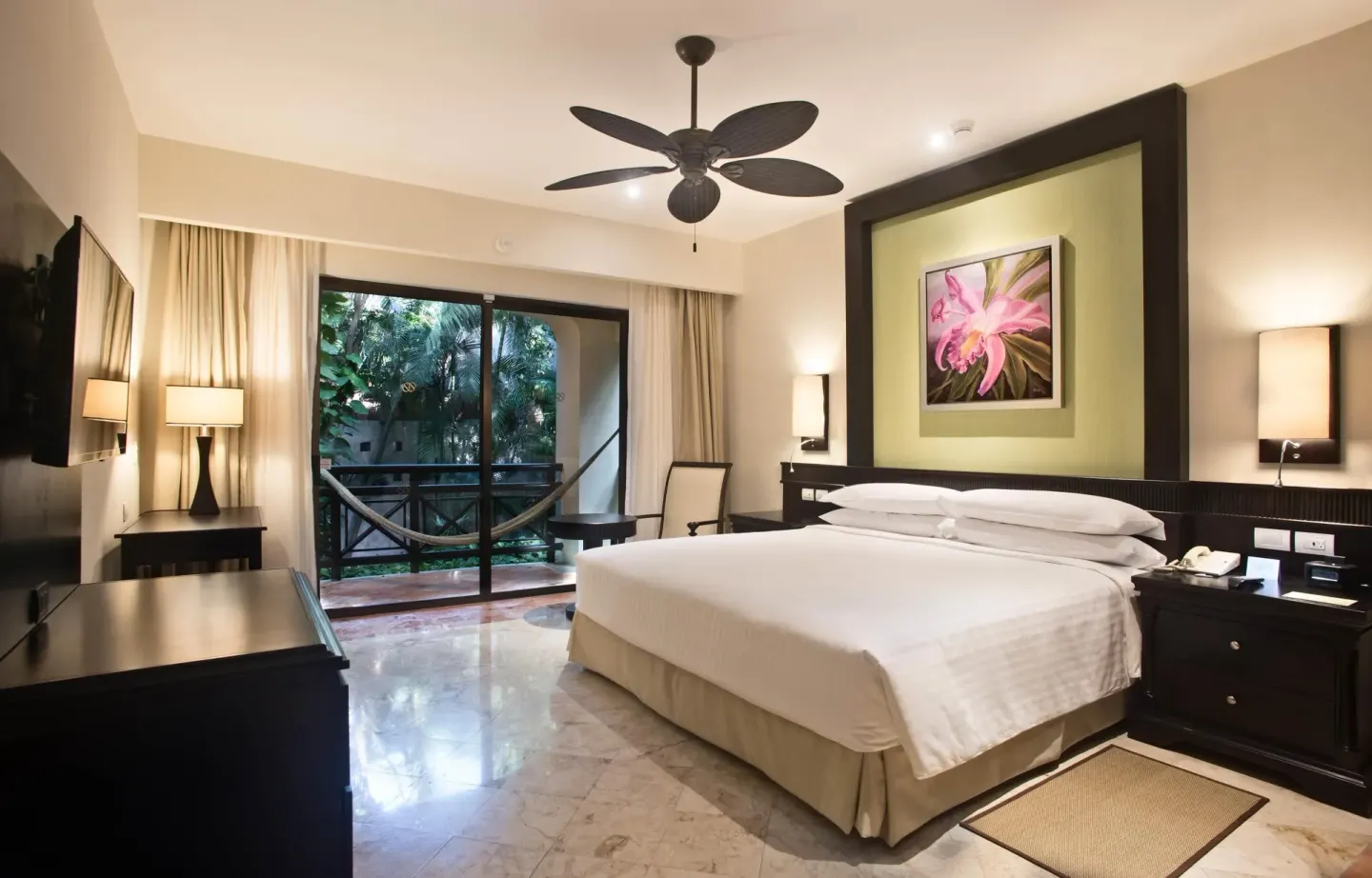 Luxury Room king bed with balcony hammock and tropical greenery at Occidental at Xcaret Destination.