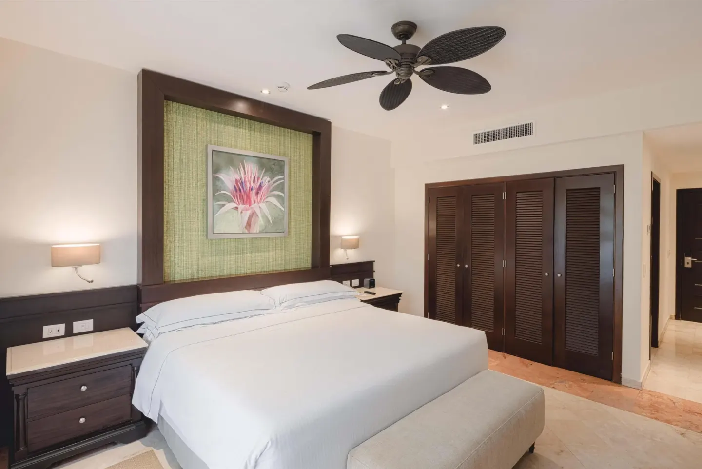 Luxury Room king bed, louvered closets, and ceiling fan at Occidental at Xcaret Destination.