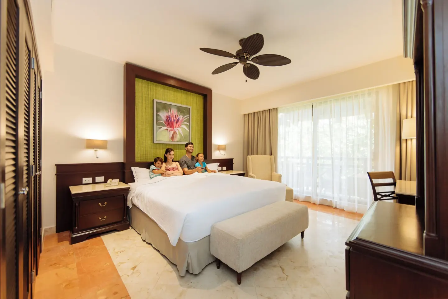 Luxury Room king bed with family seating and large curtained window at Occidental at Xcaret Destination.