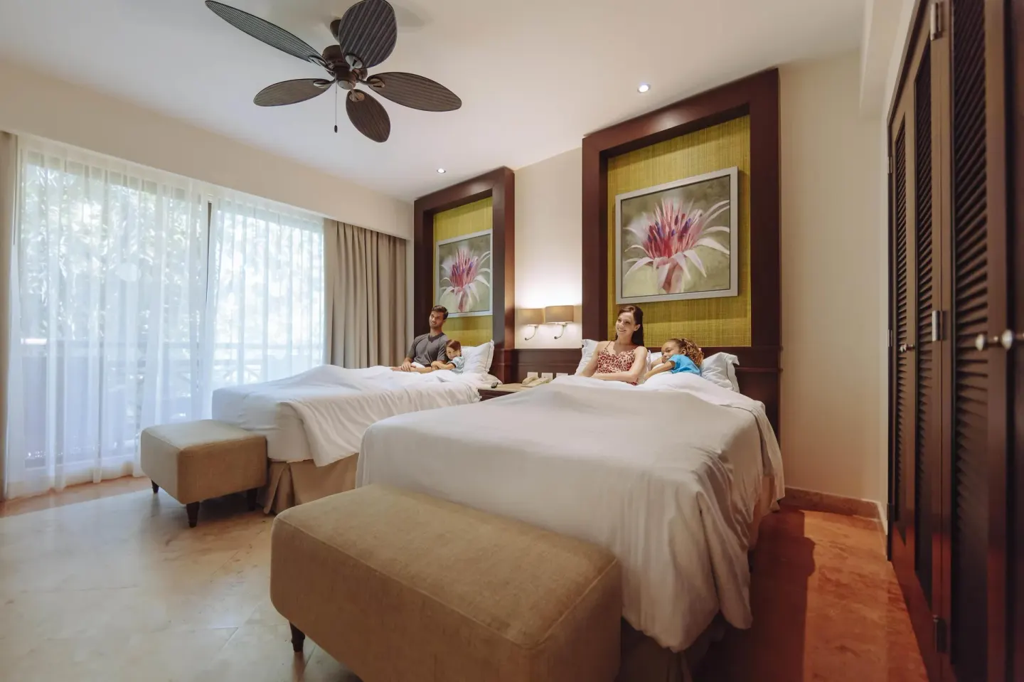 Luxury Room with two beds, benches, and bright window curtains at Occidental at Xcaret Destination.
