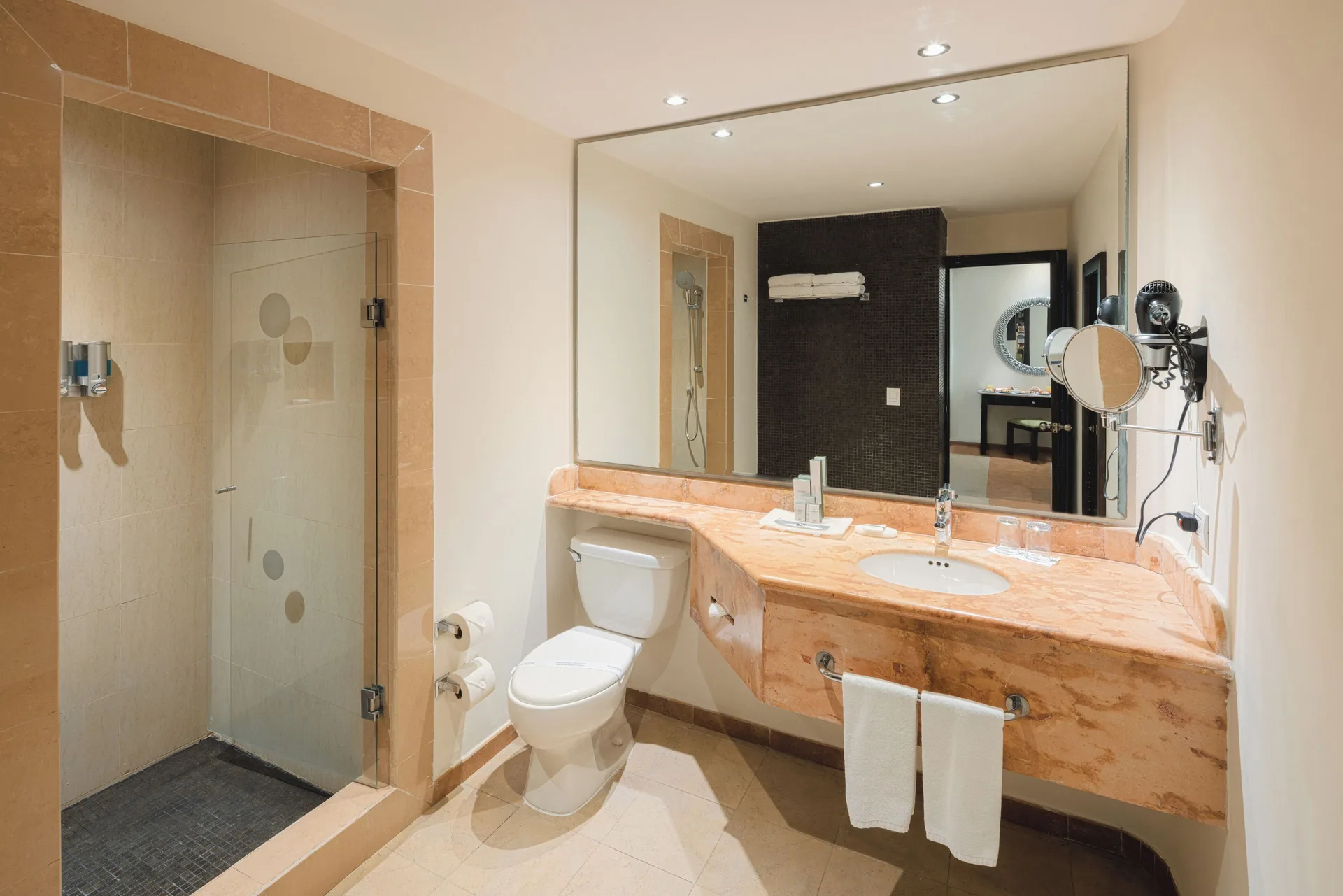 Royal Level Suite bathroom with glass shower, vanity and toilet at Occidental at Xcaret Destination.