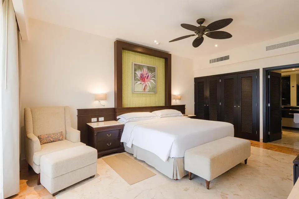 Royal Level Suite bedroom with king bed and seating at Occidental at Xcaret Destination.