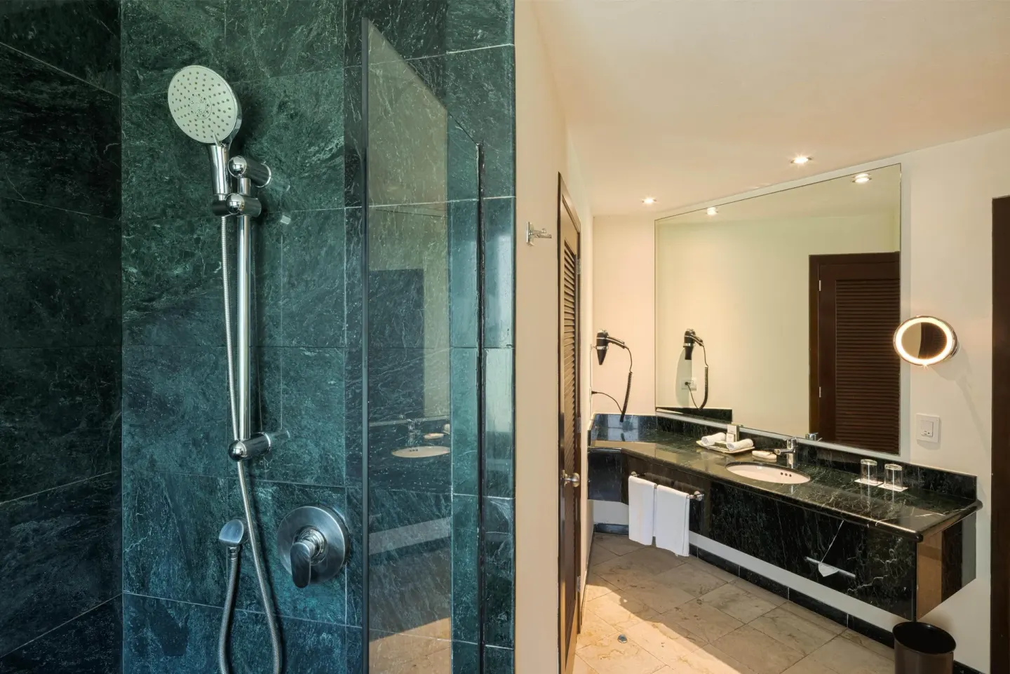 Royal Suite bathroom with glass shower, double vanity and large mirror at Occidental at Xcaret Destination.